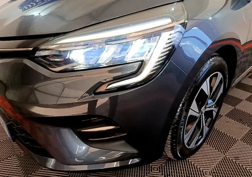 Gros plan sur l'avant droit gris foncé d'une Renault Clio 2022 avec phares LED et jante alliage moderne.