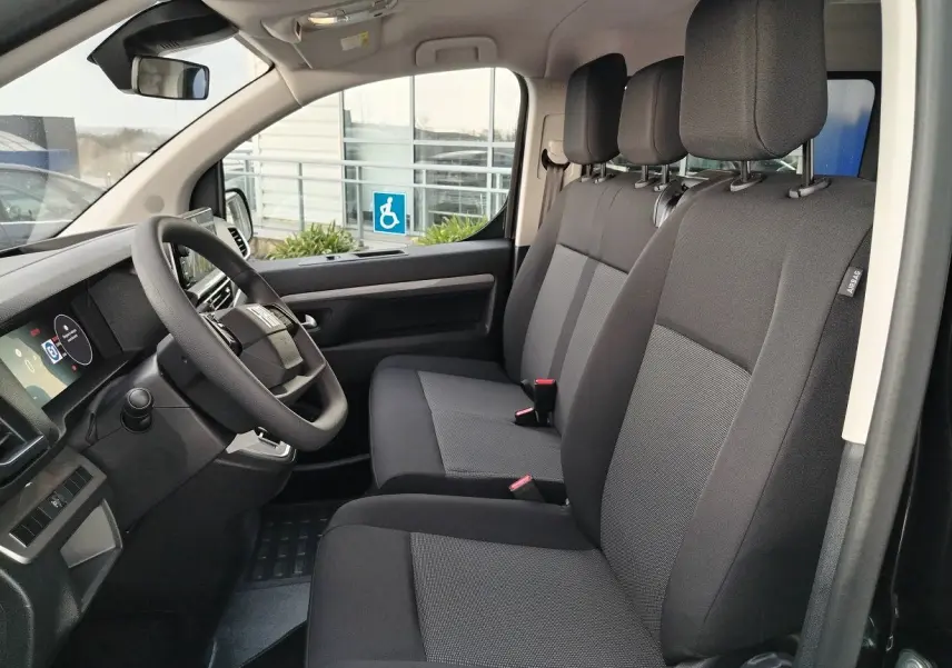 Vue intérieure côté conducteur du Fiat Ulysse 2026, sièges tissu gris foncé avec tableau de bord moderne.