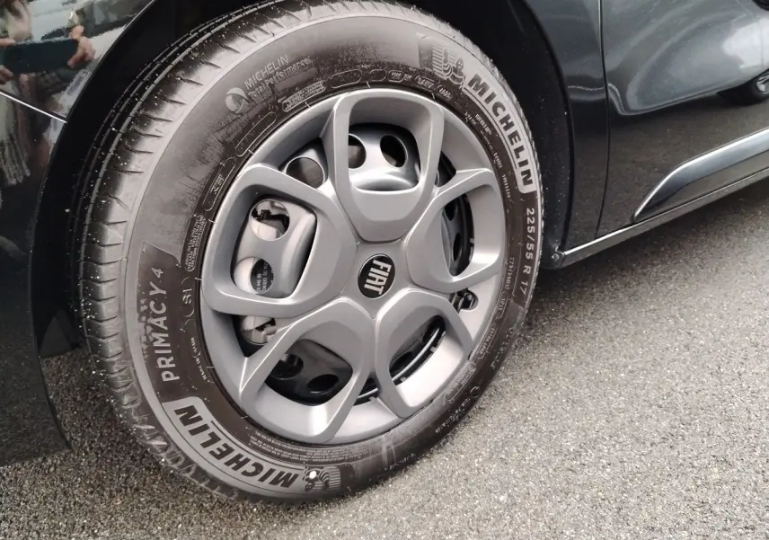 Gros plan sur la roue avant gauche d’un FIAT ULYSSE noir Perla, avec jante grise et pneu Michelin Primacy 4.