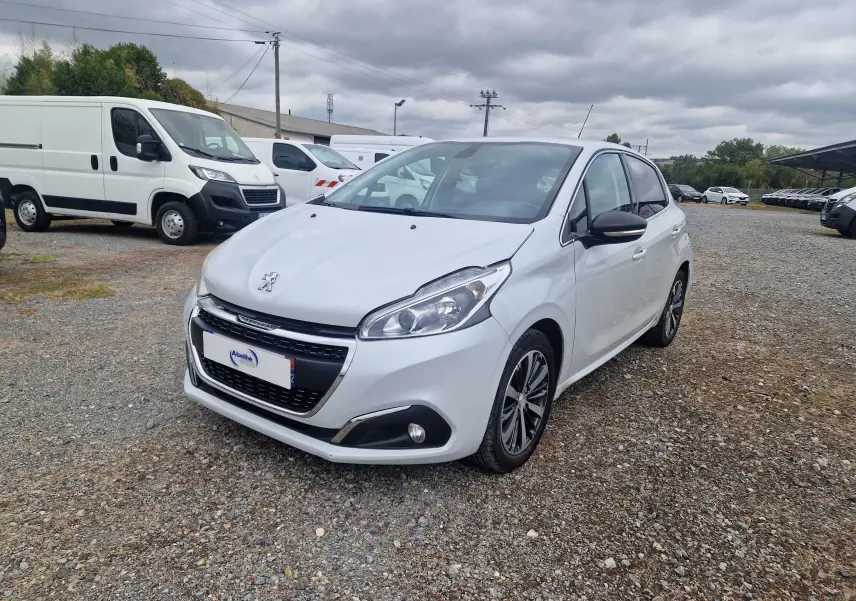 Peugeot 208 blanc nacré vue 3/4 avant droit, avec jantes alliage bi-ton et calandre noire distinctive.