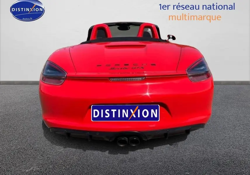 Vue arrière d'une Porsche Boxster 981 rouge avec double sortie d'échappement et becquet arrière visible