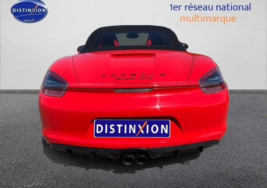 Vue arrière d'une Porsche Boxster GTS rouge avec capote noire et double sortie d'échappement centrale.