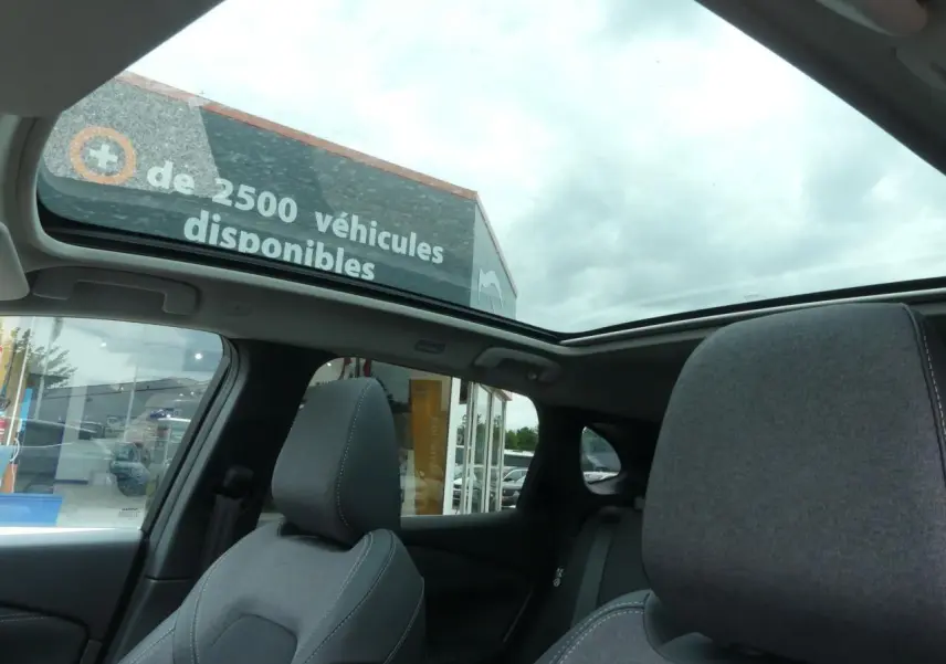 Vue intérieure du toit panoramique en verre du Nissan Qashqai gris métallisé avec sièges avant en tissu gris.