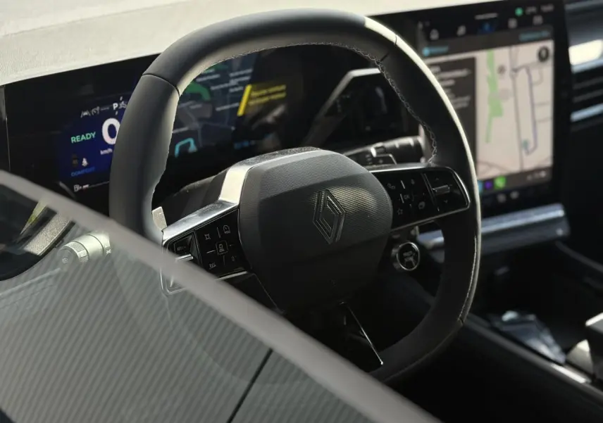 Vue rapprochée du volant en textile et Alcantara avec logo Renault, tableau de bord numérique et écran tactile du Renault Rafale E-Tech.