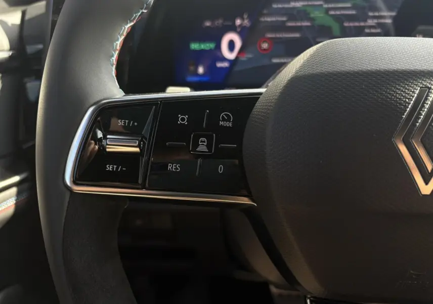 Gros plan sur le volant à droite avec commandes de régulateur, surpiqûres tricolores et logo Renault du Renault Rafale E-Tech.
