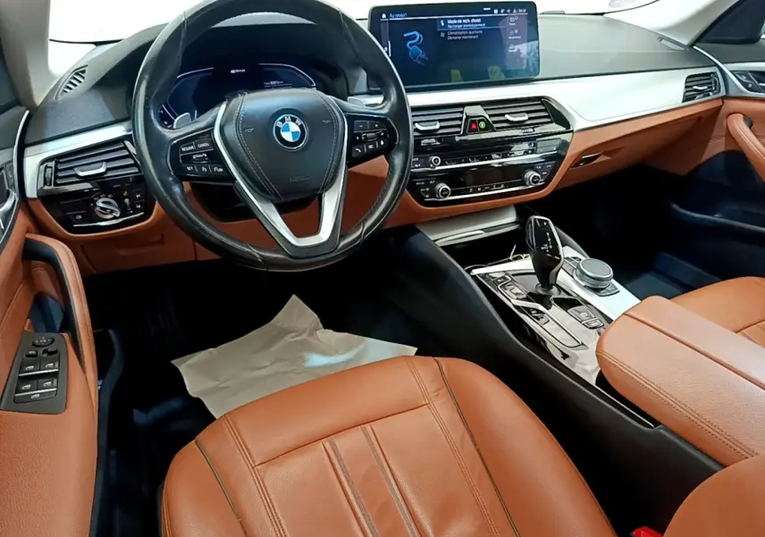 Intérieur BMW Série 5 Touring 530e 2022, vue cockpit côté conducteur, cuir marron et tableau de bord digital.