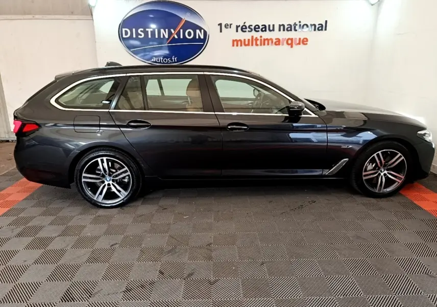 BMW Série 5 Touring 530e gris clair vue de profil côté gauche, avec jantes alliage et toit ouvrant visible.