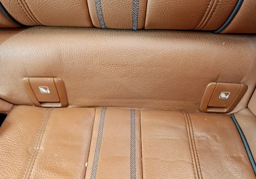 Détail des commandes de rabattement des sièges arrière en cuir marron clair dans une BMW Série 5 Touring 530e.