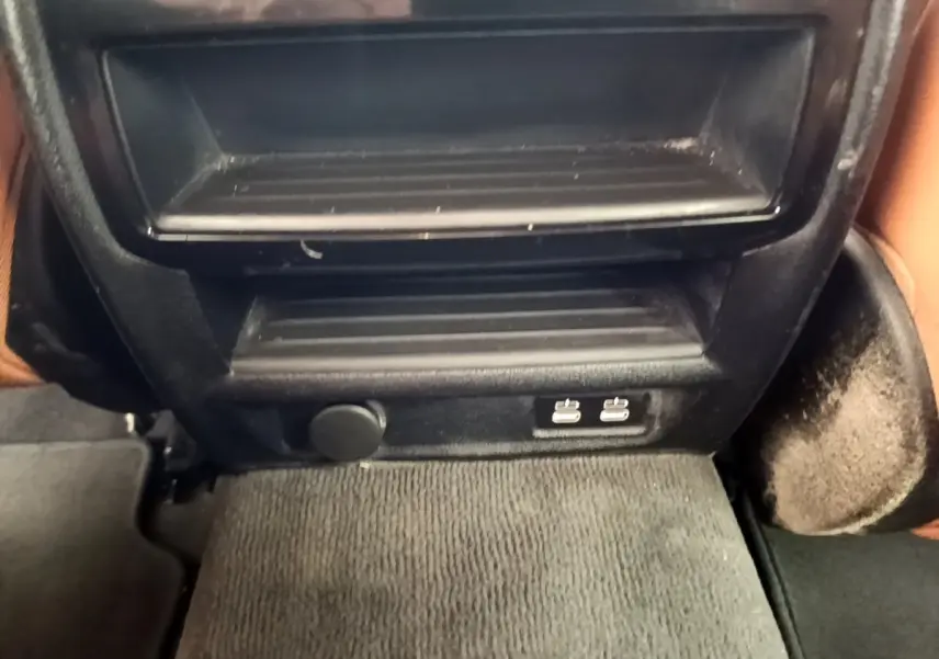 Vue rapprochée de la console arrière noire avec prises USB doubles et prise 12V dans une BMW Série 5 Touring gris clair.