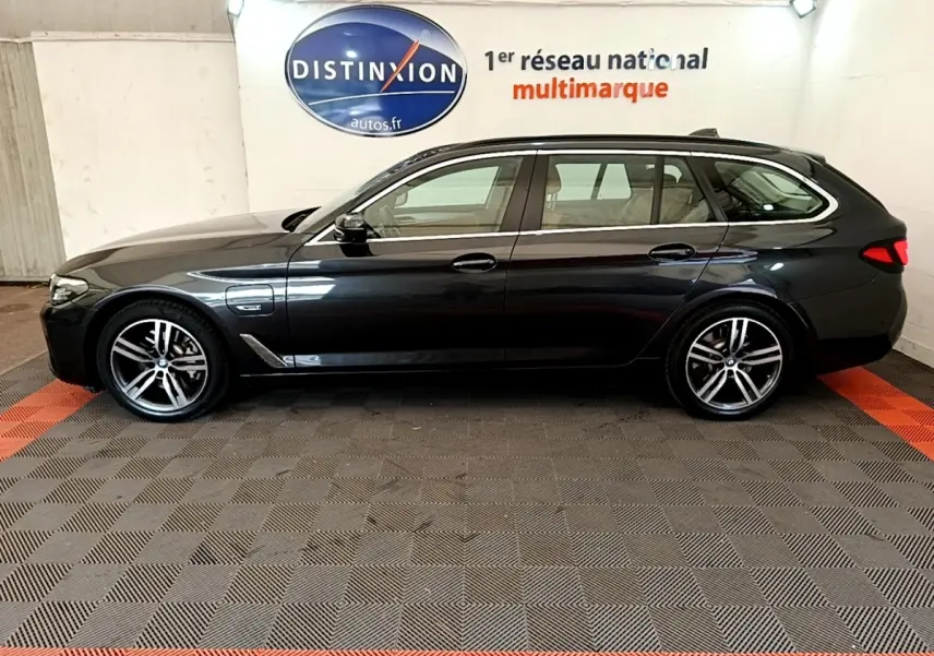 BMW Série 5 Touring 530e gris clair vue de profil côté gauche, avec jantes alliage et toit ouvrant visible.