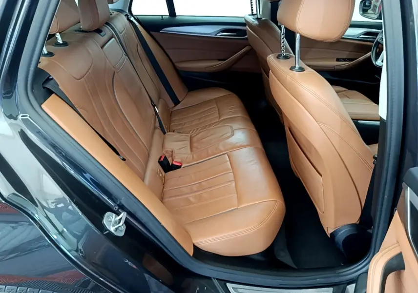 Vue intérieure côté gauche montrant les sièges arrière en cuir marron clair d'une BMW Série 5 Touring gris clair.