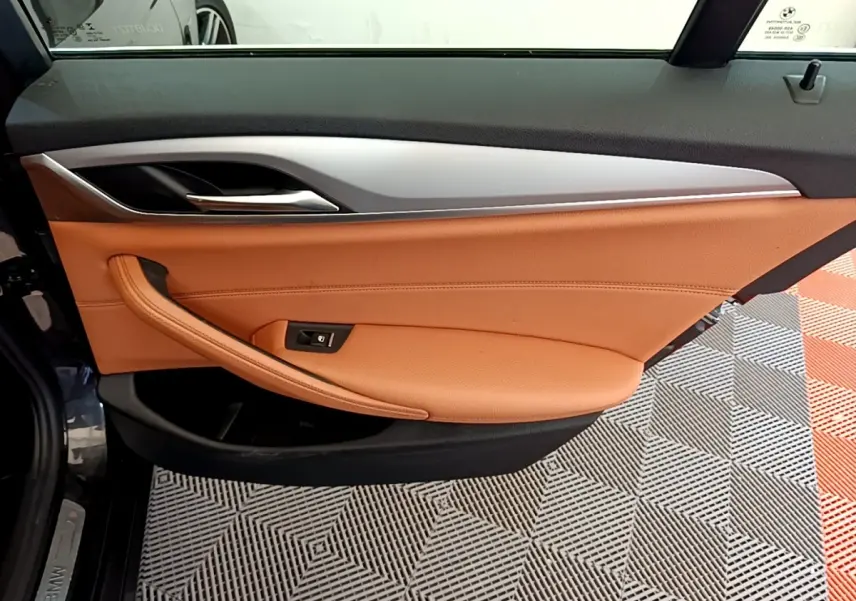 Gros plan sur la porte intérieure côté gauche de la BMW Série 5 Touring 530e 2022, garniture cuir marron clair et insert aluminium.