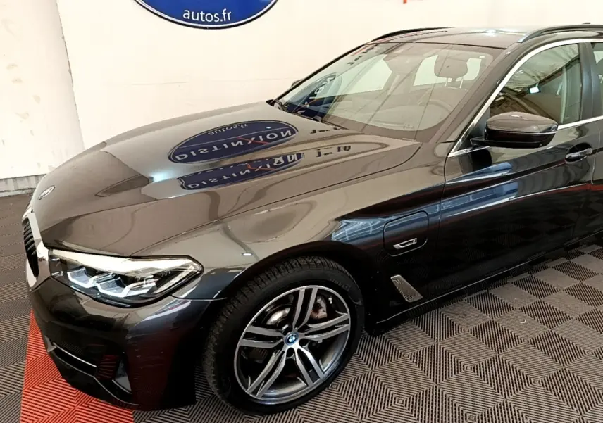BMW Série 5 Touring 530e gris clair vue 3/4 avant droit, mettant en valeur les jantes alliage et les phares LED.
