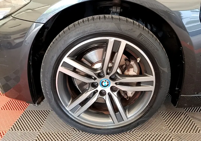 Gros plan sur la roue avant droite gris clair d'une BMW Série 5 Touring 530e avec jante alliage et logo BMW central.