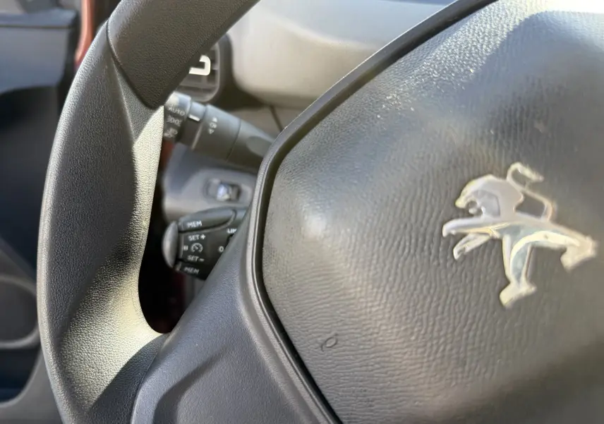 Gros plan sur le volant noir avec logo Peugeot du Rifter 2019, montrant aussi les commandes au volant côté gauche.