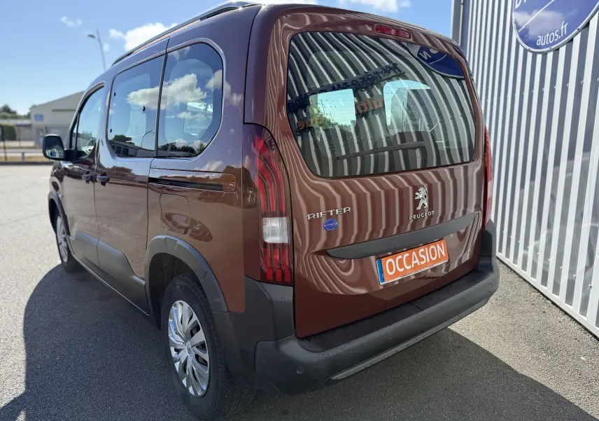 Vue 3/4 arrière droite du Peugeot Rifter Copper Metallic, avec hayon fermé et plaque "OCCASION" visible.