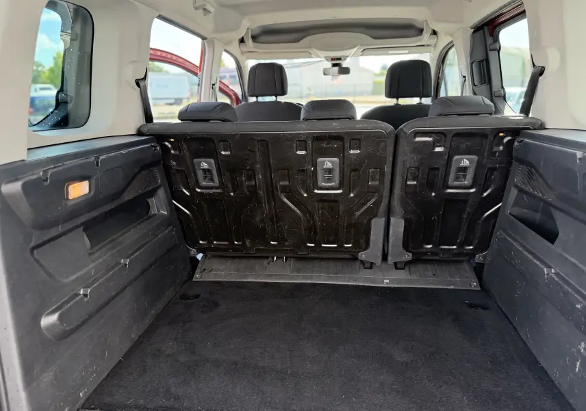 Vue intérieure depuis le coffre du Peugeot Rifter Copper Metallic, montrant les sièges arrière relevés et l’espace de chargement.