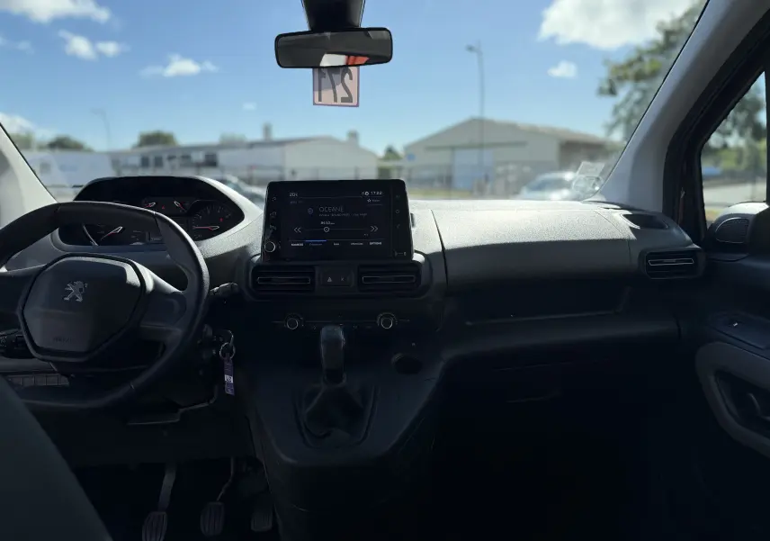 Vue intérieure frontale du Peugeot Rifter Copper Metallic, mettant en valeur le tableau de bord avec écran tactile et volant à gauche.