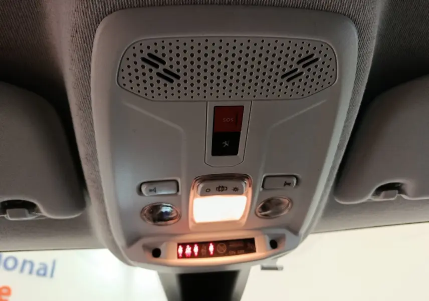 Vue intérieure en plongée sur le plafonnier gris avec bouton SOS et éclairage allumé dans une Peugeot 208 2020.