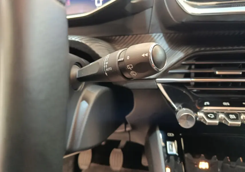 Gros plan sur la manette d’essuie-glace côté gauche du tableau de bord noir d’une Peugeot 208 2020.