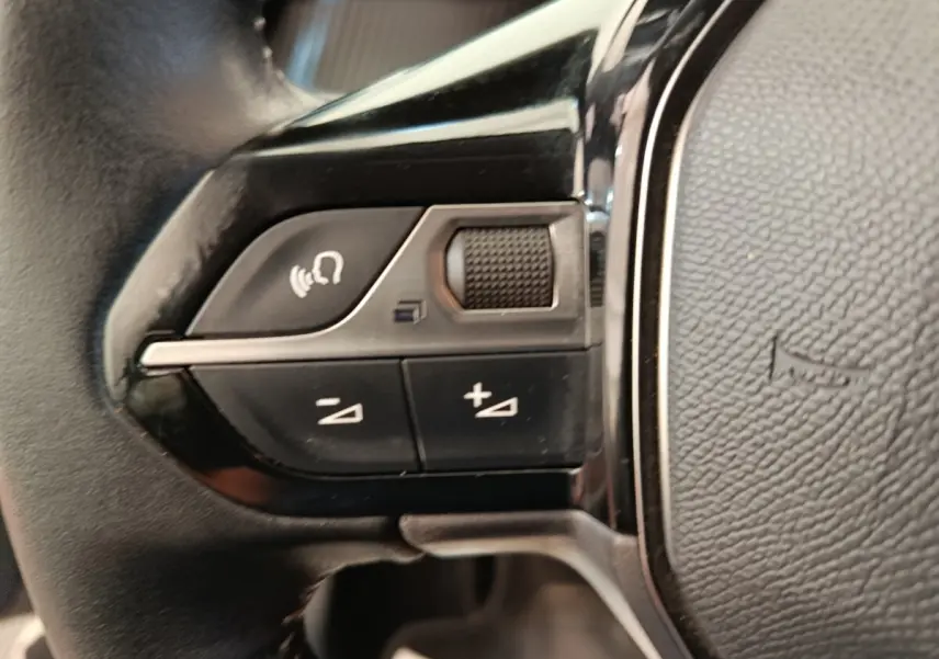 Gros plan sur les commandes multifonctions en cuir du volant gauche d'une Peugeot 208 2020, finition Allure Business.