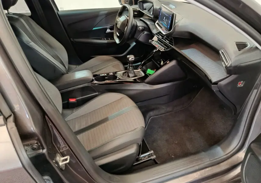 Vue intérieure côté conducteur de la Peugeot 208 2020, sièges gris, volant cuir multifonctions et écran tactile central.