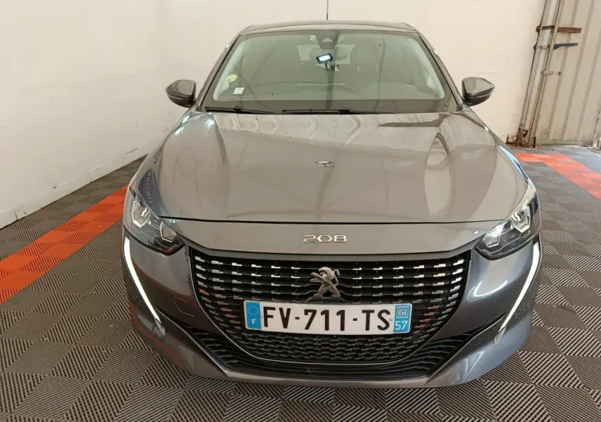 Peugeot 208 gris vue de face, avec calandre noire et feux LED en forme de griffes distinctifs.