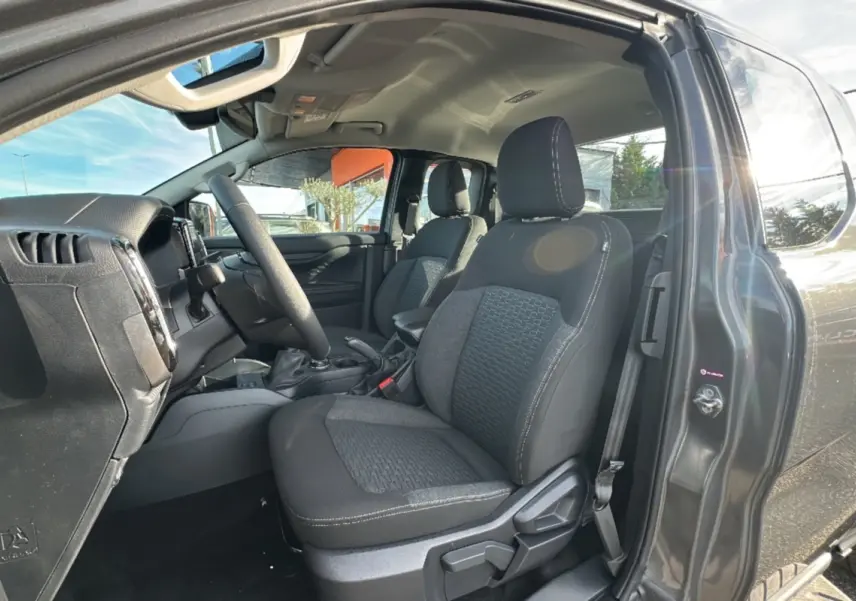 Vue intérieure côté conducteur du Ford Ranger gris iconic 2026, sièges tissu noir avec surpiqûres blanches visibles.
