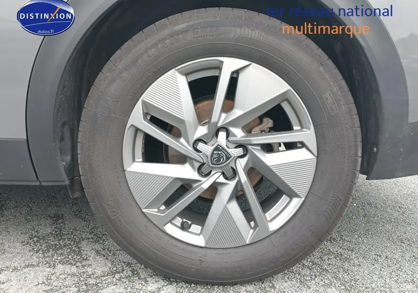 Gros plan sur la jante alu grise avec logo Peugeot, montée sur un pneu Goodyear, partie latérale du Peugeot 408 gris Sellenium.