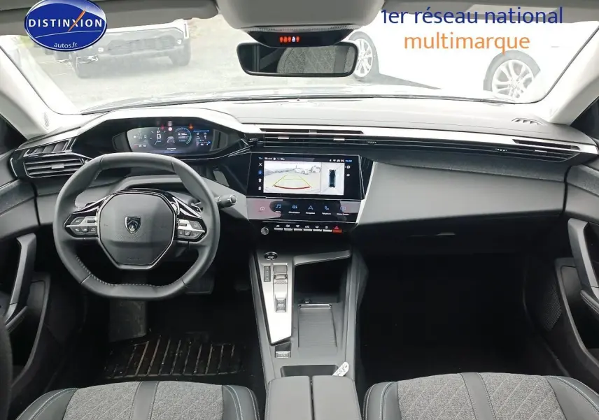 Vue intérieure avant du Peugeot 408 Hybrid 145 allure 2024, tableau de bord moderne avec écran tactile et volant multifonction.
