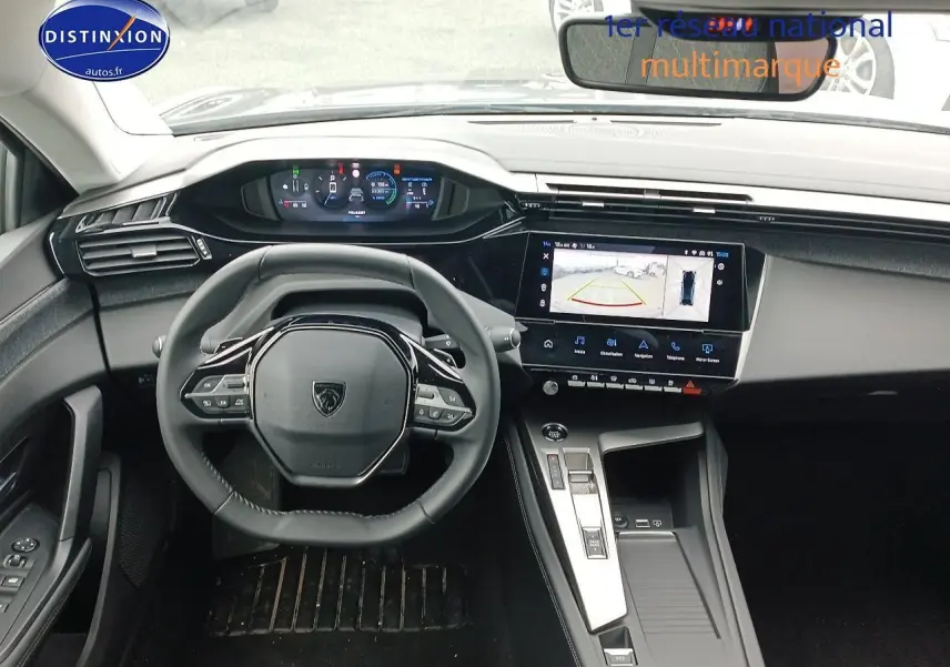 Vue intérieure avant centrée sur le volant cuir multifonction et l'écran tactile affichant la caméra de recul de la Peugeot 408 gris sélénite.