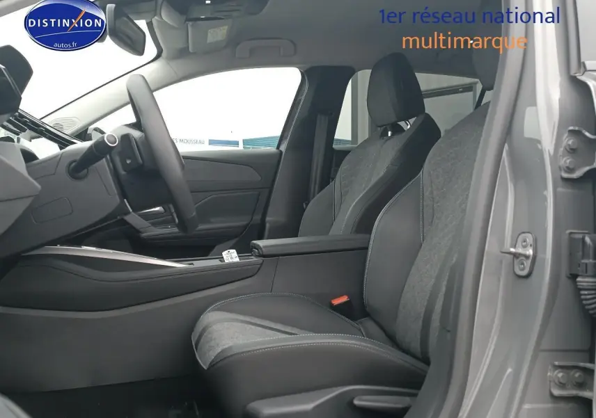 Vue intérieure côté conducteur de la Peugeot 408 Hybrid gris sellenium, avec sièges bi-matière et accoudoir central ouvert.