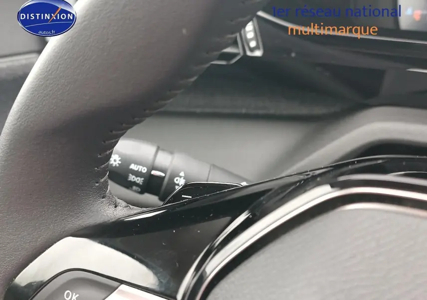 Gros plan sur le volant cuir noir multifonction d’une Peugeot 408 Hybrid 145 allure gris sélénite, avec commandes au volant visibles.