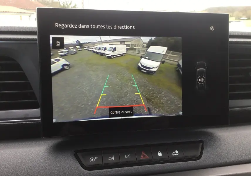 Écran central du Renault Master blanc 2026 affichant la caméra de recul avec vue sur plusieurs véhicules blancs en arrière-plan.