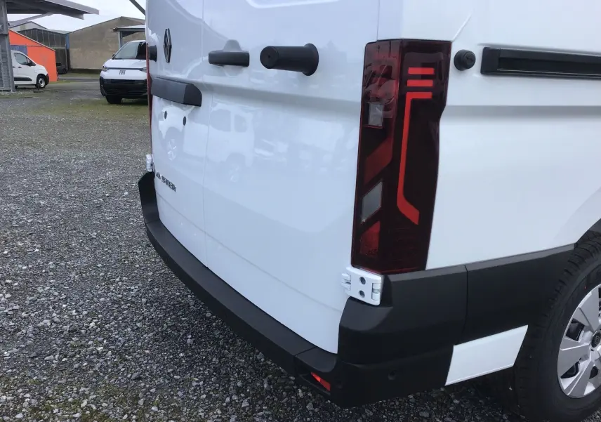 Vue 3/4 arrière droite du Renault Master blanc, mettant en valeur le feu arrière vertical et le pare-chocs noir robuste.