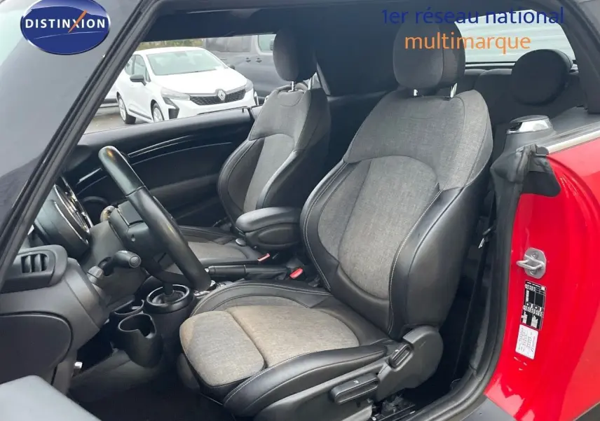 Vue intérieure côté conducteur d'une MINI Cabriolet F57 rouge chili, sièges bi-matière gris et noir visibles.