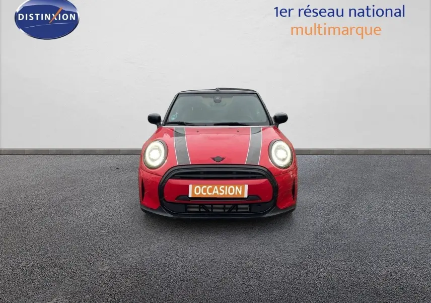 Vue frontale d'une MINI Cabriolet F57 rouge chili avec bandes noires sur le capot et phares allumés.