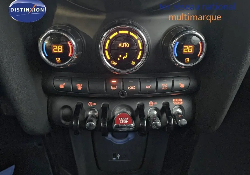 Gros plan sur la console centrale de la MINI Cabriolet rouge chili, montrant les commandes de climatisation et le bouton start/stop.