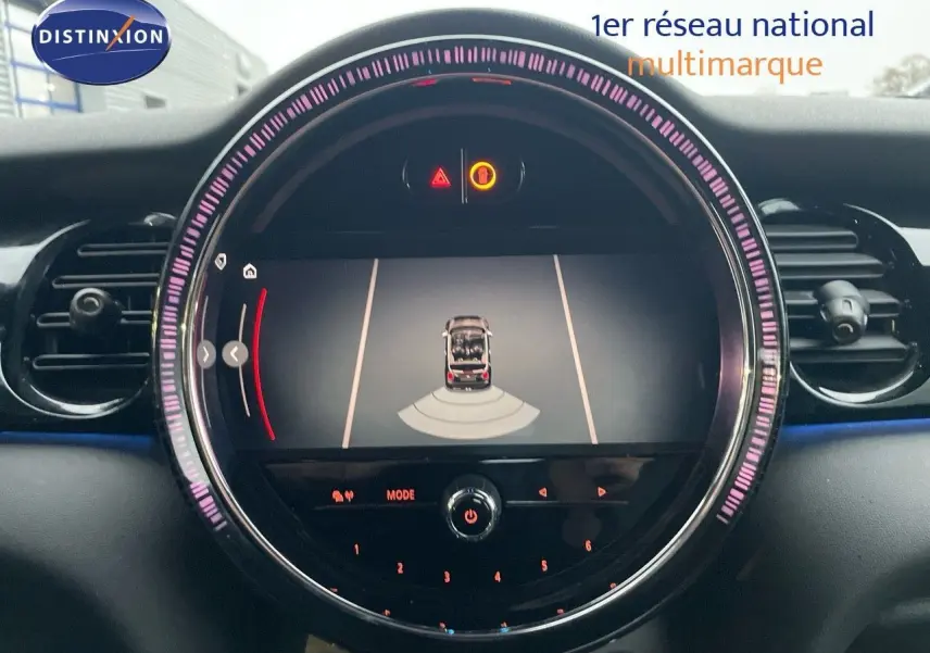 Vue rapprochée de l'écran central du tableau de bord d'une MINI Cabriolet rouge chili, affichant l'aide au stationnement.