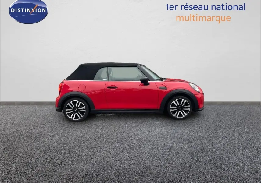 Profil gauche d'une MINI Cabriolet F57 rouge chili 2023 avec capote noire et jantes bi-ton élégantes.