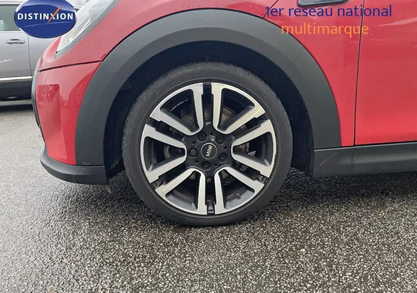 Gros plan sur la roue avant gauche d'une MINI Cabriolet F57 rouge chili, soulignant la jante alu bicolore design moderne.