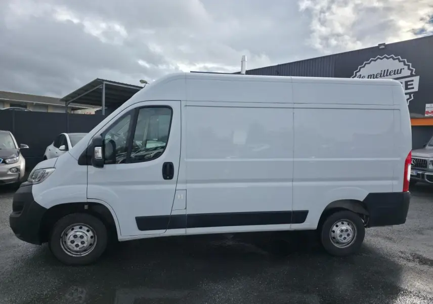 Profil côté gauche d'un fourgon Opel Movano blanc avec panneaux latéraux bois et porte coulissante tôlée.
