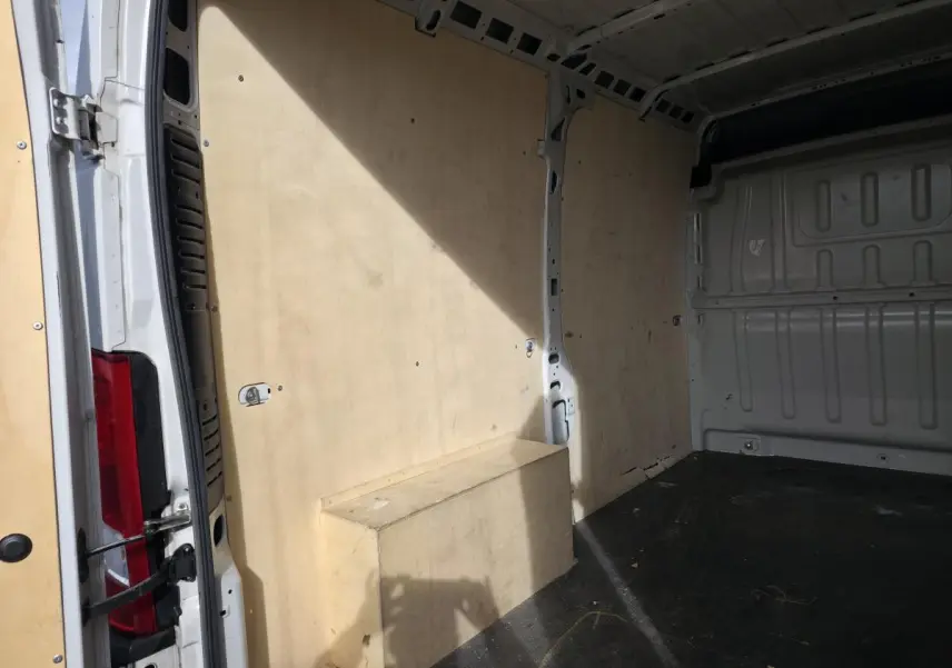 Intérieur du fourgon blanc Opel Movano, vue latérale gauche montrant les panneaux et plancher bois.