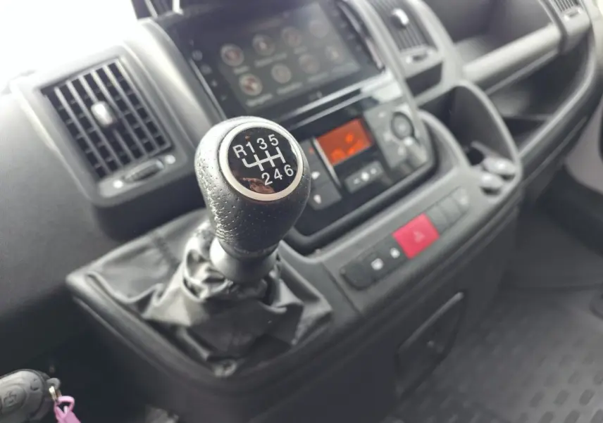 Gros plan sur le levier de vitesses manuel et la console centrale noire de l'intérieur du fourgon Opel Movano blanc.