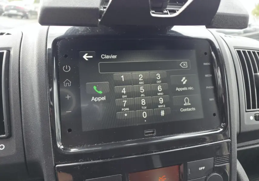 Écran tactile central affichant un clavier d'appel dans l'habitacle noir d'un Opel Movano Fourgon blanc.