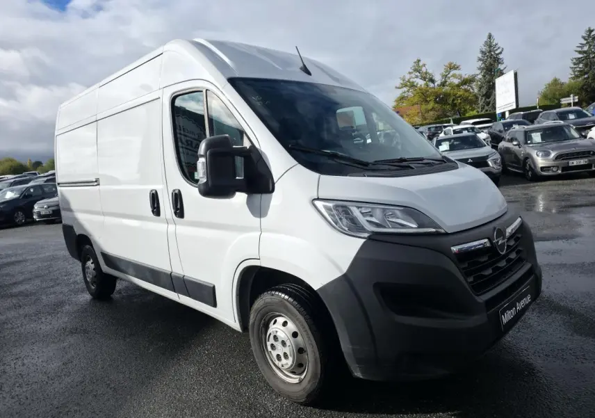 Opel Movano Fourgon blanc vu en 3/4 avant droit avec pare-chocs noir et portes latérales tôlées.