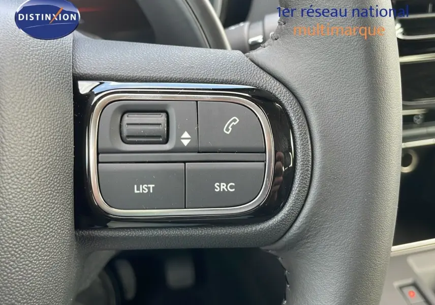 Gros plan sur les commandes gauche du volant cuir noir du Citroën C5 Aircross blanc, avec boutons audio et téléphone.