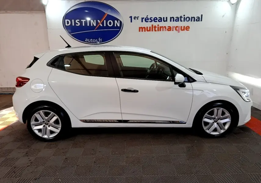 Profil droit d'une Renault Clio Business blanche 2021, avec jantes alliage et vitres teintées, en intérieur showroom.