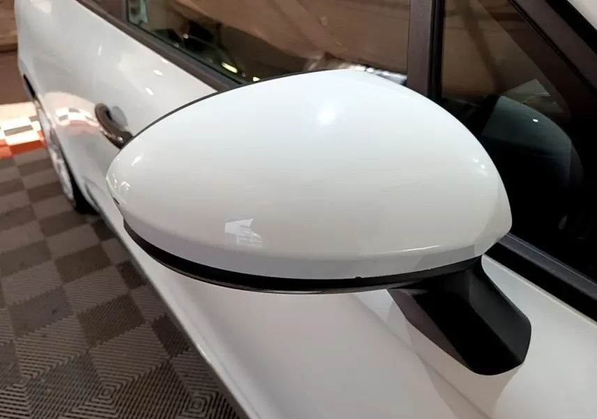 Rétroviseur droit blanc en gros plan sur Renault Clio Business 2021, avec portière et vitre partiellement visibles.