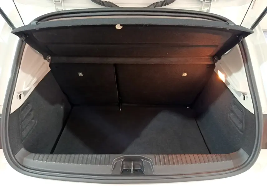 Coffre ouvert vu de face d’une Renault Clio Business blanche, montrant l’espace de chargement vide et la lumière intérieure.